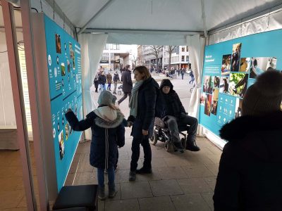 The photo shows visitors of the assistance dog exhibition looking at the information boards.