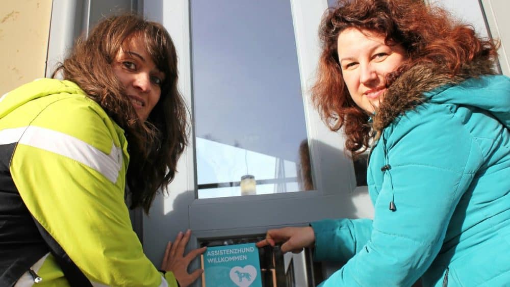 Sandra Herrmann (left) from the Saale-Orla District Association for the Disabled and Equal Opportunities Officer Nadine Hofmann place the "Assistance Dog Welcome" sticker at the main entrance of the District Office in Schleiz.
Photo: Photo: Brit Wollschläger