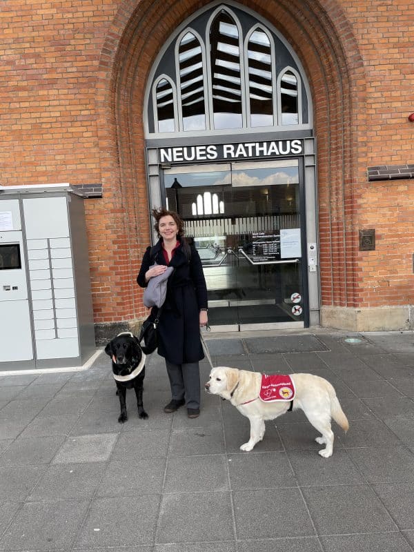 Our public relations officer, Dr Hannah Reuter, with two assistance dogs in front of Celle Town Hall.