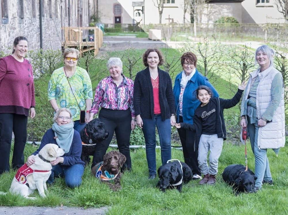 Eine Gruppe mit Assistenzhunden steht im Innenhof des Aktivhotels