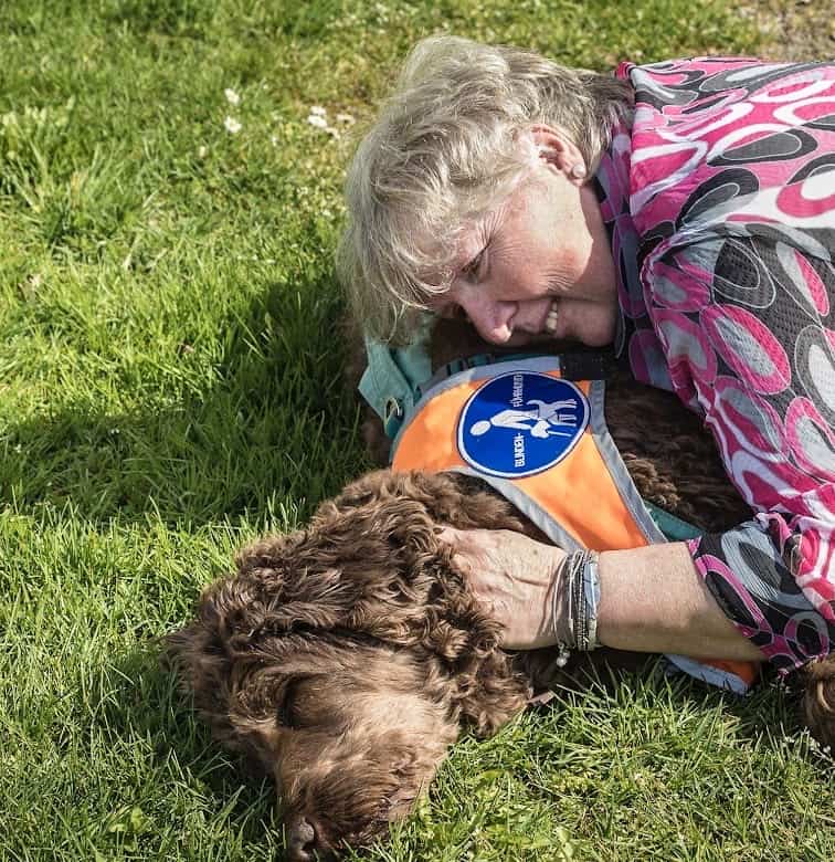 Michaela liegt mit ihrem Führhund im Garten auf dem Rasen.