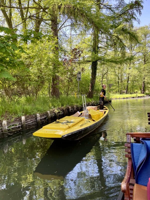 Auf dem Wasser ist ein Spreewaldkahn mit dem Zeichen der Post zu sehen. Die Zustellerin stakt den Kahn selbst