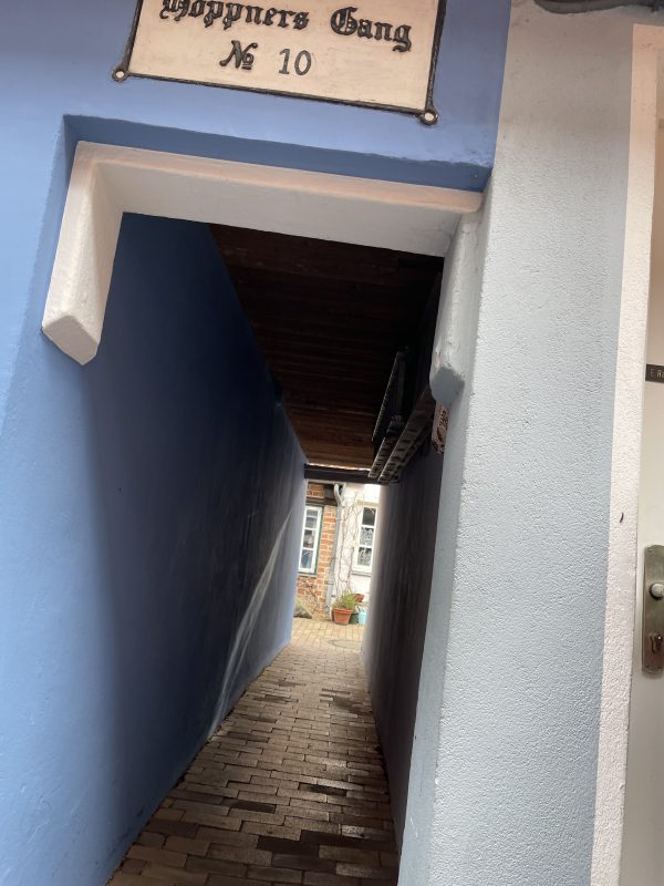 Ein sehr schmaler Gang durch ein Haus mit blauer Fassade