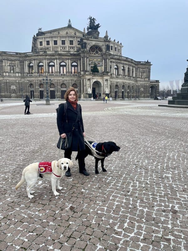 Im Hintergrund sieht man die Semperoper und im Vordergrund steht Dr. Reuter mit Daika und Mascha.