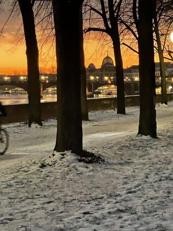 Blick über die Elbe, im Hintergrund das Dresdenpanaorama und ein orangefarbener Morgenhimmel.