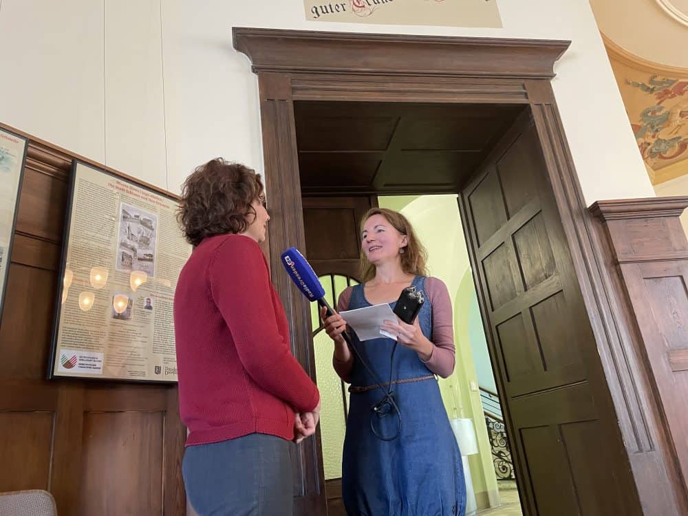 Dr. Hannah Reuter, Public Relations Officer, is interviewed by a journalist on the sidelines of the press conference.